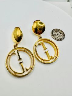 Fabulous designer earrings are hallmarked Gucci made in Italy and dated 1992.  I believe they are in celebration of Gucci's 40th Anniversary and are limited edition.   Paoli Gucci (1931-1995) was the chief fashion designer in the Italian House of Gucci family business. He is credited with creating their famous GG logo and went out in his own in the 1980's.  These bold style logo earrings are made in a gold metal in 2 parts with movement, duster or dangle style.   The top is a round gold metal circle attached to a large cutout gold hoop featuring tge famous double GG logo inside.   They are a nice large size and measure 2.5 inches long by 1-3/8 inches in diameter across the hoops.  Gently used and very good vintage condition. Although large, they are not too heavy to wear. UDPS priority shi Classic Gucci Pendant Jewelry, Gucci Family, Gucci Earrings, Italian House, Prescott Az, Metal Circle, Gg Logo, Bold Style, Ear Rings