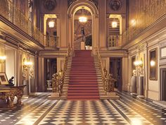 an ornately decorated hall with stairs and chandeliers