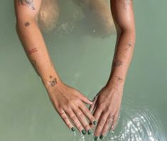 a woman's hands with tattoos are in the water and she is holding onto her hand