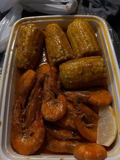 a container filled with shrimp and corn on the cob