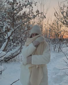 a woman standing in the snow wearing a white coat