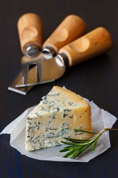 a piece of cheese sitting on top of a piece of wax paper next to a knife