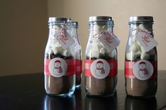 three glass jars filled with marshmallows on top of a table