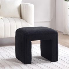 a black stool sitting on top of a white rug