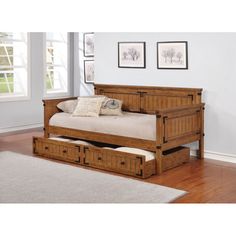 a daybed with drawers underneath it in a room next to a rug and pictures on the wall