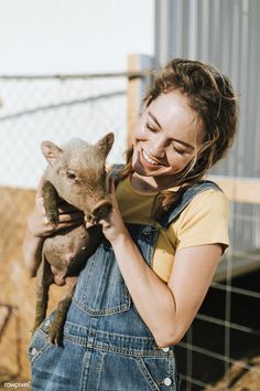 a woman holding a baby pig in her arms