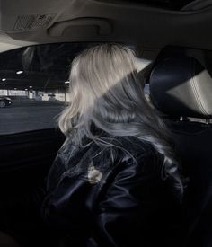 a woman sitting in the passenger seat of a car with her back to the camera