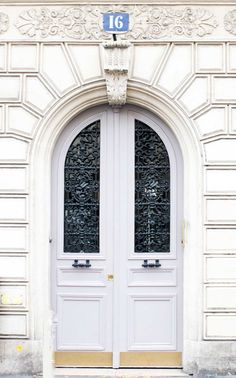 two white double doors in front of a building with a number 16 sign on it