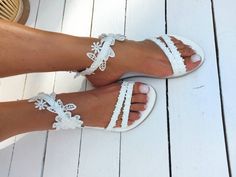 a woman's feet wearing white sandals with lace trimmings on the toes