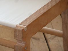 a close up of a wooden chair with white fabric on the seat and wood flooring