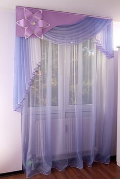 a window with sheer curtains and a flower on the curtain valance in front of it