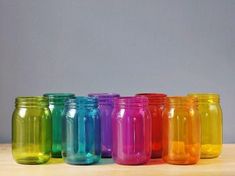 there are many different colored mason jars lined up on the table with one empty jar