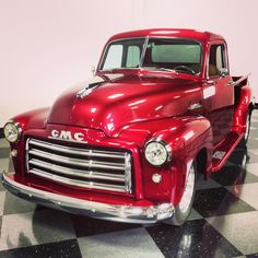 an old red truck is parked on a checkered floor