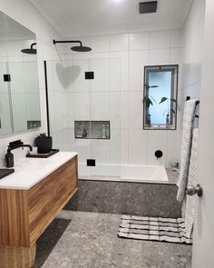 a bathroom with a sink, mirror and bathtub next to a shower head mounted on the wall