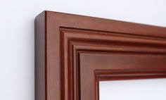 a close up of a wooden frame on a wall with white walls in the background