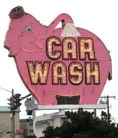 a pink car wash sign with an elephant on it's back and the words car wash written in large letters