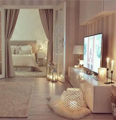 a living room with a tv and candles on the table in front of the bed