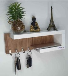 a shelf with key hooks, keys and a potted plant sitting on top of it