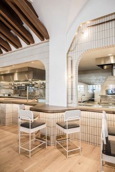 two white chairs sitting on top of a hard wood floor next to a kitchen counter