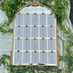 the seating chart for an outdoor wedding is displayed on a table covered in ivy and gold