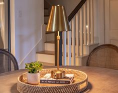 a table with a lamp and books on it in front of a stair case that leads up to the second floor