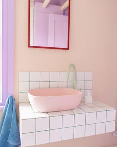 a bathroom with pink and white tiles on the counter, sink and mirror above it