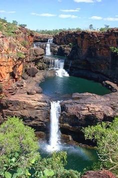 a waterfall in the middle of some rocks with water running down it's sides