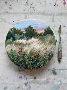 a painting on a plate next to a fork and knife with paint splatters all over it