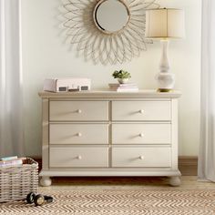 a white dresser with a mirror above it and a lamp next to it on a rug