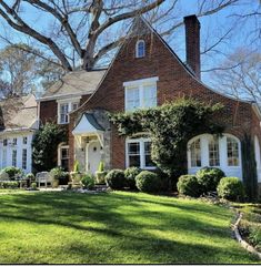 a large brick house sitting on top of a lush green field next to a tree