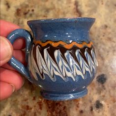 a hand is holding a blue and white coffee cup with wavy designs on the outside