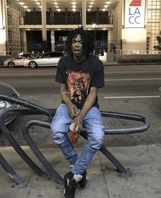 a young man sitting on top of a metal object in front of a parking lot