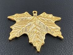 a gold maple leaf charm on a black surface