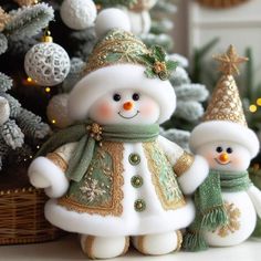 two snowmen standing in front of a christmas tree