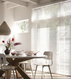 a dining room table and chairs with white blinds