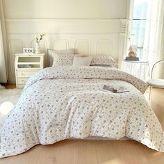 a bed with white sheets and pillows in a bedroom next to a window on the floor