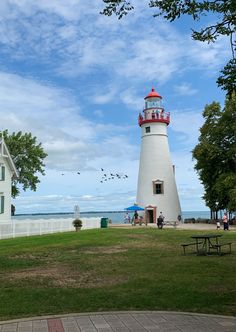 a white lighthouse with a red and blue light house in the background on a sunny day