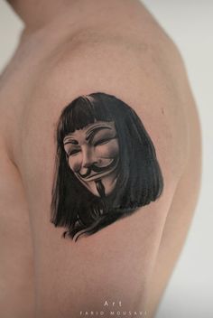 a woman with a mask tattoo on her shoulder and chest is looking at the camera