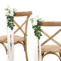 two wooden chairs with white flowers and greenery on the back one chair is made of wood