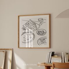 a drawing hangs on the wall next to a table with books and other items in front of it