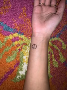 a person's arm with a small peace sign tattoo on the middle of it