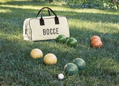 an assortment of bocce balls in the grass next to a duffel bag