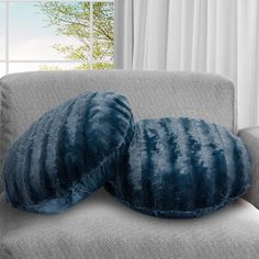 two blue pillows sitting on top of a gray couch