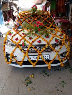 a car decorated with flowers and garlands on the side of it's face