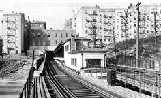 a black and white photo of a train on the tracks in front of some buildings