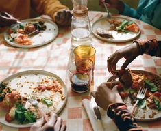 people are sitting at a table with plates of food