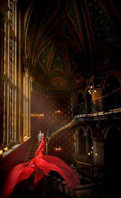 a woman in a long red dress is sitting on the stairs and looking at something