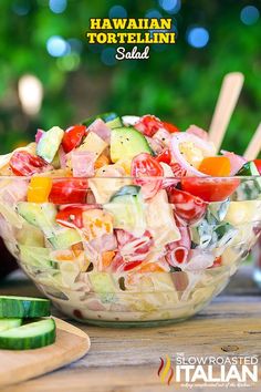 a salad with tomatoes, cucumbers and onions in a glass bowl on a wooden table