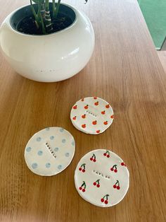 three ceramic plates sitting on top of a wooden table next to a potted plant