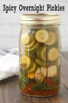 a jar filled with pickles sitting on top of a wooden table